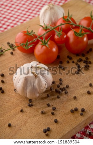 Garlic, cherry tomato and pepper seed on wooden plate on kitchen table. healthy food background.