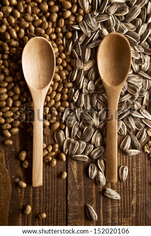 Wood spoons and cereal grains on wooden table, top view