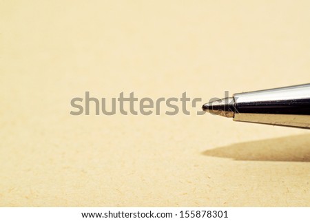 Ballpoint pen tip on yellow paper macro shot