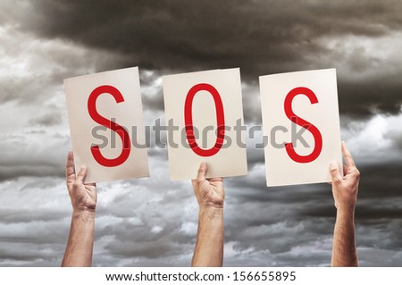 SOS message, save our souls. Human hands holding papers with printed letters SOS.