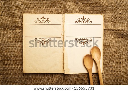 Blank recipe book and wooden spoons, top view