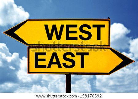 east versus west, opposite signs. Two opposite signs against blue sky background.