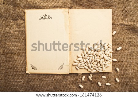Kidney beans and open book on jute canvas texture.