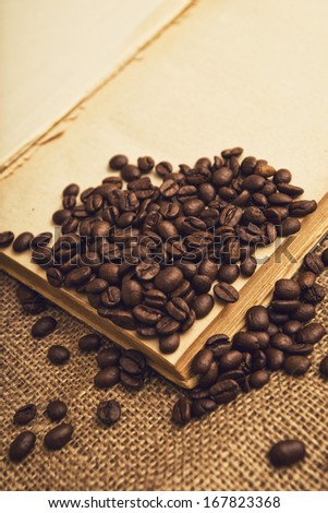 Coffee beans and open book on jute canvas texture.
