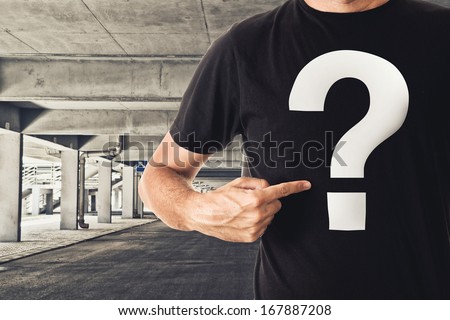 Slim tall man posing in black t-shirt with question mark in public garage