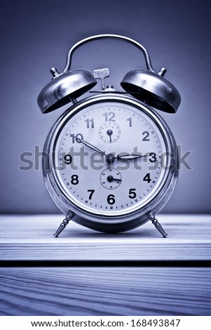 Vintage alarm clock on wooden table at night, insomnia concept.