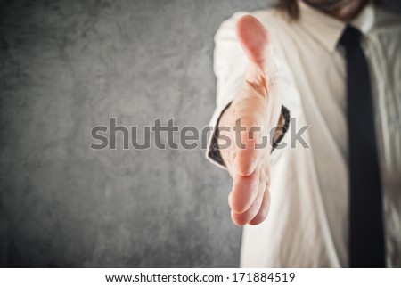 Businessman offering hand for a handshake, selective focus. Business communication, introduction or agreement concept.