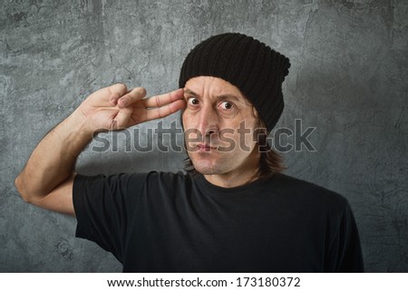 Casual man pointing his fingers to his head as if he is about to shoot himself. Suicidal tendencies.