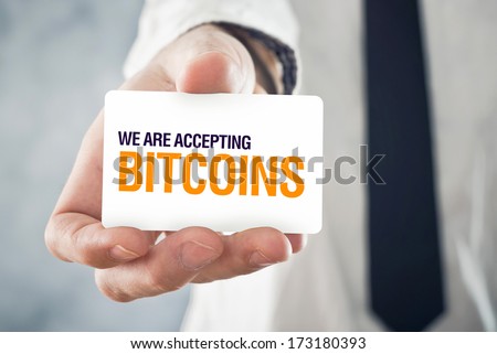 Businessman holding card with title WE ARE ACCEPTING BITCOINS. Selective focus on card and fingers.