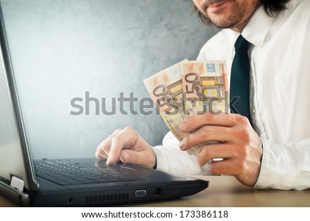 Making money online, businessman with laptop computer is earning money over internet.