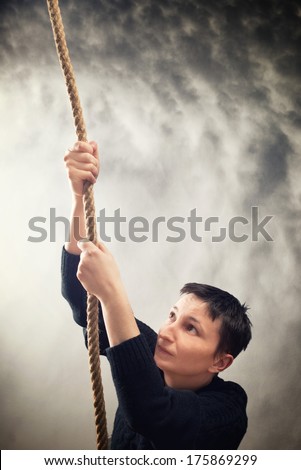 Woman climbing up with rope. Overcoming problems, obstacles and difficulties in life metaphor.