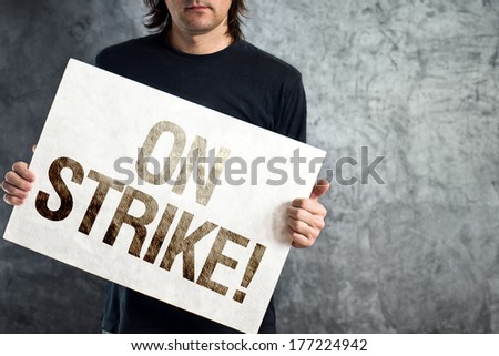 Man holding banner with ON STRIKE printed protest message.
