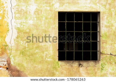 Large old window with broken panes on old cracked wall