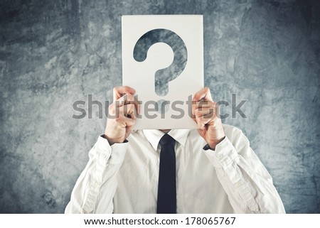 Businessman holding paper with printed question mark in front of his face