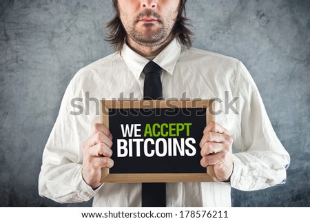 Businessman holding board with title WE ACCEPT BITCOINS as form of payment.