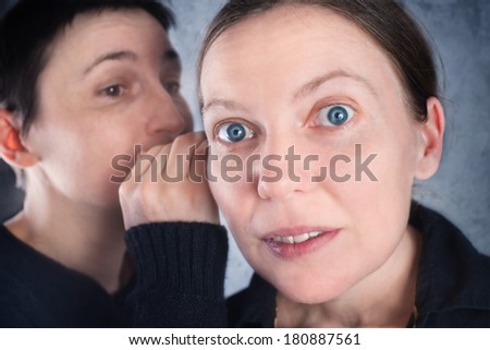 Two women gossiping, telling secrets or hearsay stories to one another.