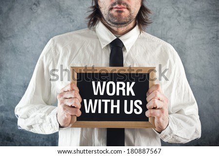 Businessman holding blackboard with WORK WITH US title. Business concept.