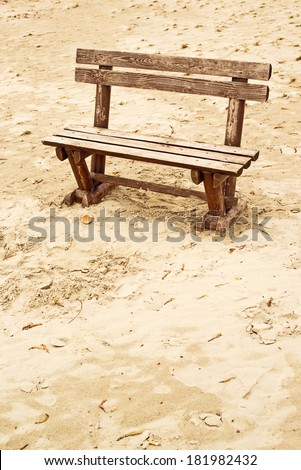 Empty wooden bench on the beach in cloudy weather. Concept of loneliness, emptiness, solitude.