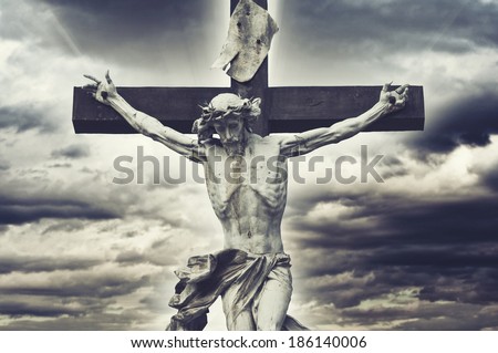 Crucifixion. Christian cross with Jesus Christ statue over stormy clouds. religion and spirituality concept.