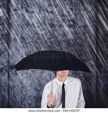Businessman with black umbrella protecting from the rain. Business concept for protection, safety, security in hard times of economic depression.