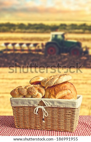 Bread in wicker basket with tractor and agricultural field in background. Making bread conceptual image.