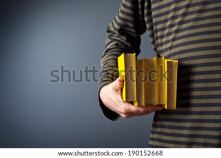 Casual man holding stack of old yellow hard cover books