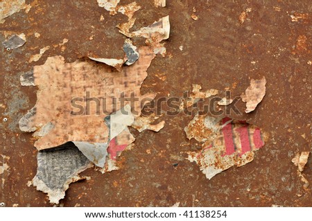 Torn poster paper glued on an obsolete corroded metal plate