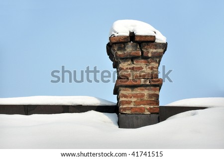 Old brick chimney on house roof covered with snow.