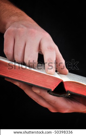 Reading Bible. Close up of a man holding a Bible, focus on finger pointing a verse with his index finger
