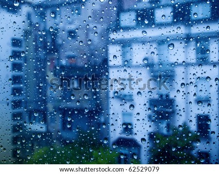 Drops of rain on a window pane, buildings in background.