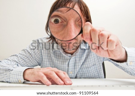 Funny image of a business person with a magnifying glass, one eye is enlarged.