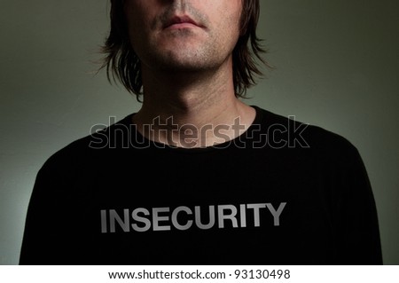 Shy insecure man. Shyness, introversion, insecurity, solitude conceptual image. Man wearing a black shirt with Insecurity title on his chest.