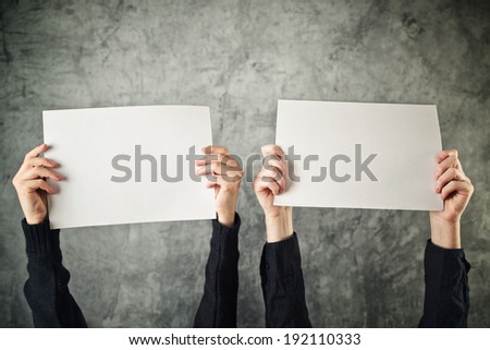 Two women holding blank paper posters above their heads