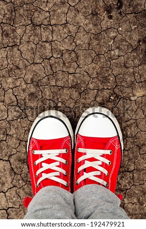 Boy in red sneakers standing on the ground, from above. Growing up with whole life ahead concept. Making first step.