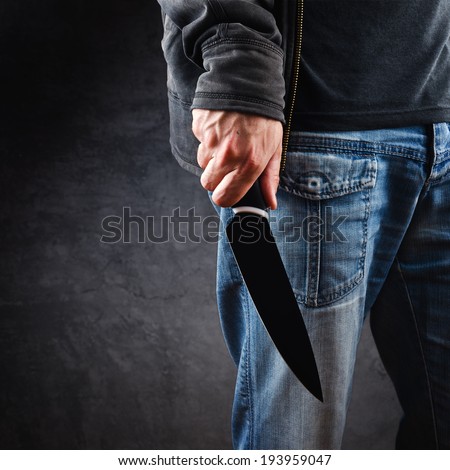 Robber holding knife - a killer person with sharp knife about to commit a homicide, murder scenery.