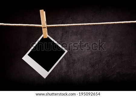 Photography paper with instant polaroid photo frame attached to rope with clothes pins. Copy space for your image.