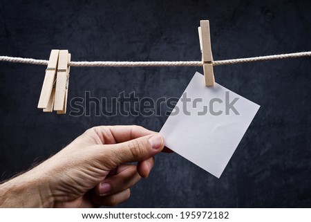 Hand picking Blank note paper attached to rope with clothes pins, copy space for your text or image or product placement.