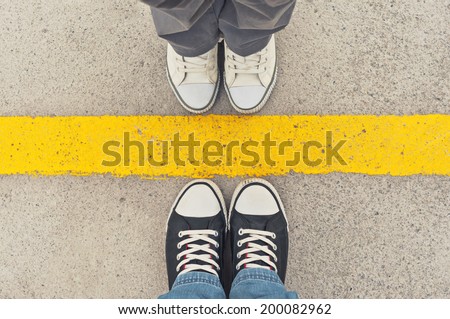 Sneakers from above. Male and female feet in sneakers from above, standing at dividing frontier line.