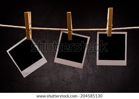 Photography paper with instant polaroid photo frames attached to rope with clothes pins. Copy space for your image.