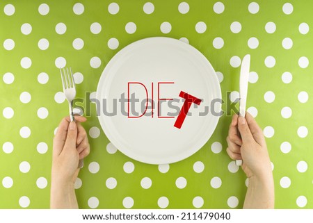 Female hands at dinner table holding fork and a knife above plate as dieting concept Word Diet becoming Die referring to health issues that diet mistakes can cause Female hands at dinner table holding fork and a knife above plate as dieting concept Word Diet becoming Die referring to health issues that diet mistakes can cause