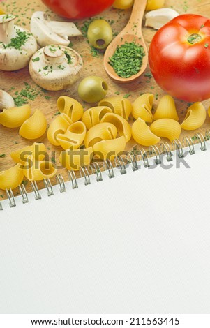 Garlic Parsley Mushroom Tomato Pasta Recipe Book on wooden board in the kitchen. Food preparation background.