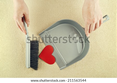 Top View of Female Hand sweeping heart shaped paper from the floor with brush cleaner.