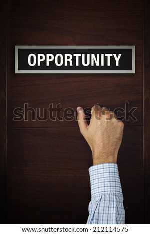 Male hand is knocking on Opportunity wooden door, conceptual image. Visitor or guest is at the door.
