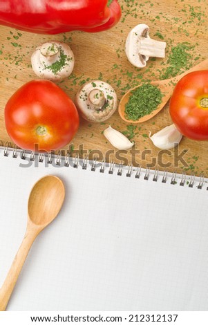 Garlic Parsley Mushroom Tomato And Paprika Recipes Book on wooden board in the kitchen. Food preparation background.