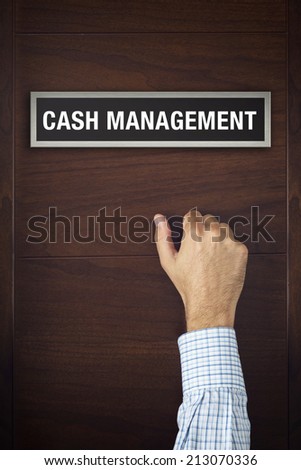 Male hand is knocking on Cash Management wooden door, conceptual image. Visitor or guest is at the door.