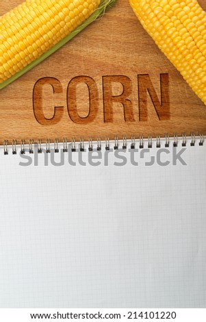 Corn Maize Cobs and recipe Book as copy space on wooden table, top view