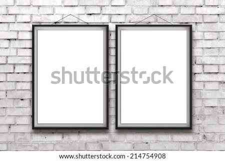 Two blank vertical painting or posters in black frame hanging on white brick wall. Painting proportions match international paper size A.