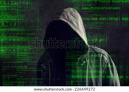 Faceless hooded anonymous computer hacker with programming code from monitor, deep web concept
