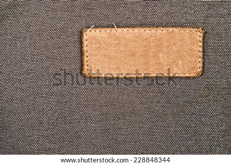 Blank Leather Label Tag on cotton fabric material texture background.