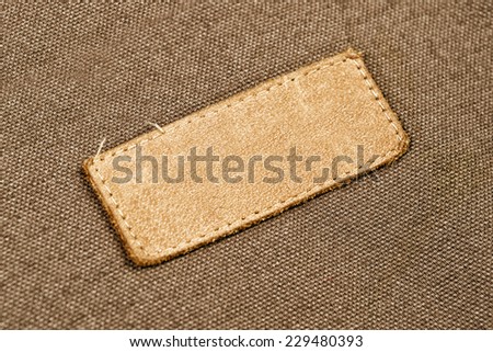 Blank Leather Label Tag on cotton fabric material texture background.